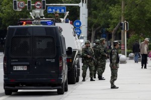 In this Friday, May 23, 2014 photo, armed Paramilitary policemen stand guard next to their Armored personnel carrier parked near the People's Square in Urumqi, in China's northwestern province of Xinjiang. A human rights group says 100,000 Chinese troops are headed to the restive province. (AP Photo/Andy Wong)